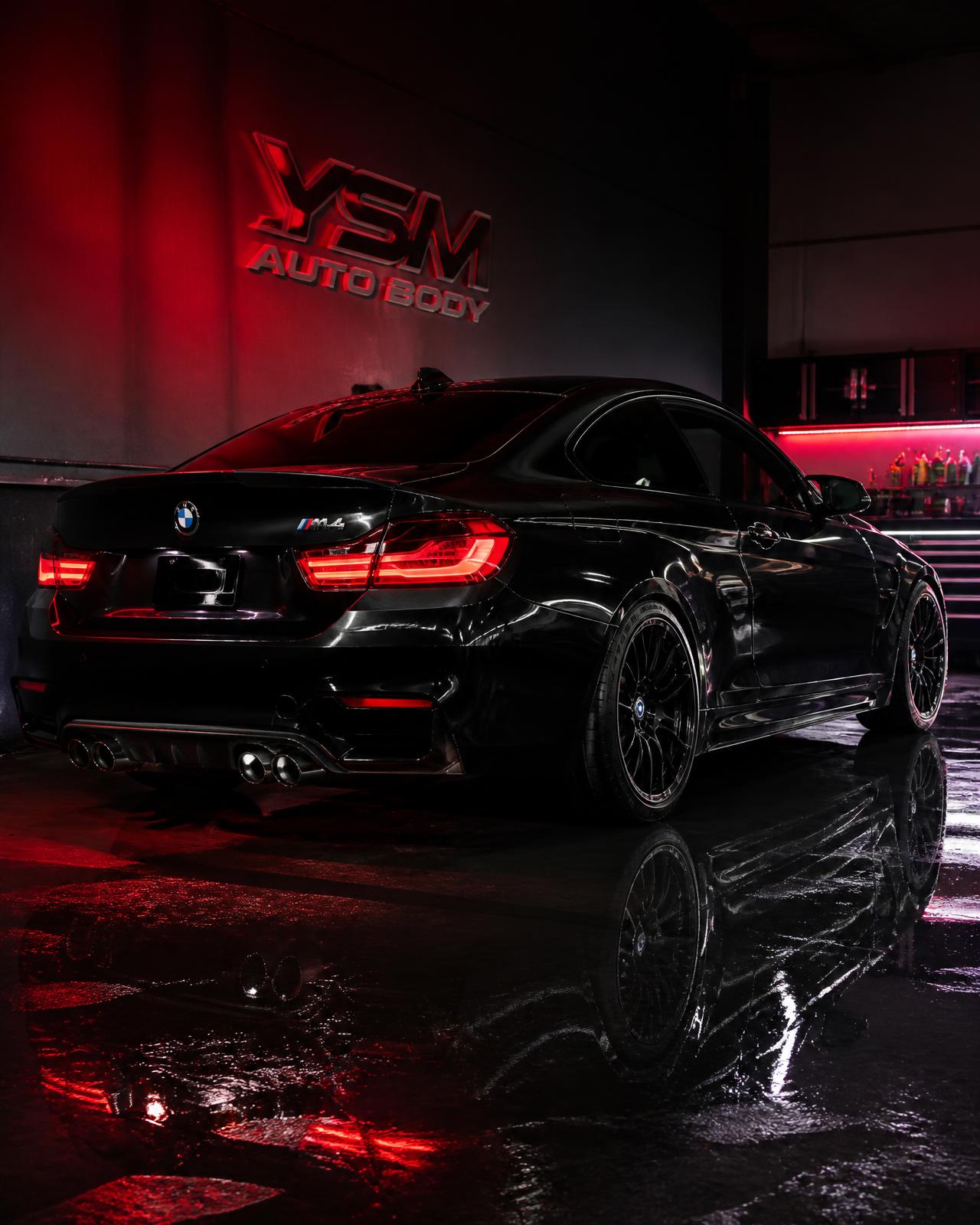 Freshly painted black BMW M4 inside New Era Customs' Bellflower paint shop